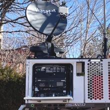 A person sets up a FirstNet compact rapid deployable in a parking lot