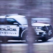 A Farmville Police Department sport utility vehicle driving down the road, captured through the trees.
