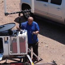 A man sets up a Compact Rapid Deployable for use in a desert area 