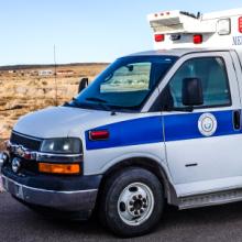 A Navajo Nation EMS ambulance parked on a street near an open field in New Mexico