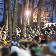 A group of people gathered in a wooded area attending the annual Groundhog Day ceremony