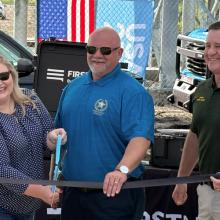 AT&T SE President Joe York, U.S. Representative Kat Cammack, FirstNet Authority Board Chairman Sheriff Adkinson, Dixie County Sheriff Darby Butler, and AT&T President of FirstNet & Public Sector Mobility Scott Agnew standing under a FirstNet by AT&T tent, holding a ribbon and large scissors for a ceremonial event launching a new cell tower in Horseshoe Beach, Florida