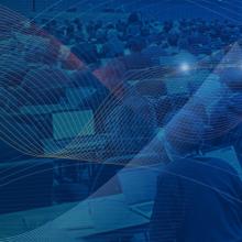 3GPP begins Release 19 work for public safety as Release 18 progress continues A large group of people dressed in business attire seated at conference tables while taking notes on electronic devices at a 3GPP plenary session; a network overlay of lines is shown waving across the photo.