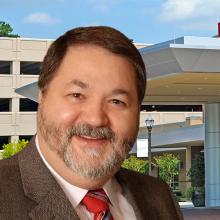 How to maintain patient care during communications outages with FirstNet A hospital emergency entrance, headshot of Paul Bowling, Emergency Manager at University of Maryland Capital Region Health, a FirstNet compact rapid deployable