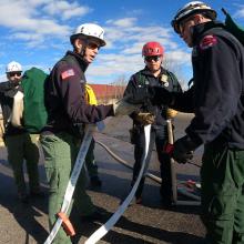 Fire on the mountain: FirstNet connects responders to Colorado wildfire Boulder responders talk while holding a fire hose in a parking lot; City of Boulder staff member wheels out a FirstNet Compact Rapid Deployable