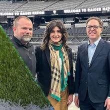 A football sits on a football field’s green turf; Assistant Secretary Alan Davidson, NTIA, and FirstNet Authority staff pose in Raiders’ Allegiant Stadium in Las Vegas