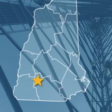 The State of New Hampshire, with outlined county borders and star locating Antrim, New Hampshire; a cell tower.