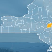 The state of New York, with outlined county borders; a cell tower.