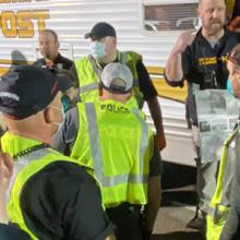 A group of first responders wearing yellow vests and medical masks gather outside an emergency response vehicle preparing to assist after a tornado near Jonesboro, Arkansas