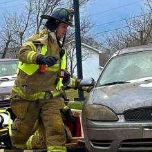 An EMS responder from the Bristol Kendall Fire Protection District with a stretcher at a damaged vehicle