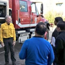 Firefighters talk to a group in front of an attack engine at the FirstNet Lab.