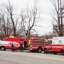 Two firetrucks, an ambulance, and other emergency vehicles gather at an incident by the side of the road