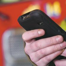 Firefighter holds smartphone in front of fire vehicle