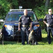 Three police officers standing in front of three Hazelton Police Department vehicles, each holding the leash of a German shepherd dog. Three police officers standing in front of three Hazelton Police Department vehicles, each holding the leash of a German shepherd dog.