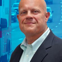 An ambulance driving down a busy highway; Jon Olson headshot An ambulance driving down a busy highway; Jon Olson headshot