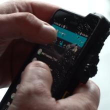 A first responder uses an application on a smartphone. A first responder uses an application on a smartphone.