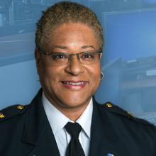 Headshot of Renee Gordon; background of 9-1-1 workstations; icon with chief’s hat and “From the Command Center”