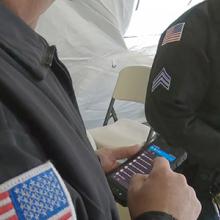 Two officers in uniform look down at FirstNet-enabled devices