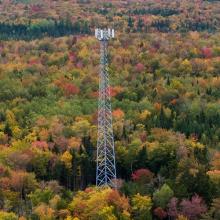 FirstNet Announces Initial Network Buildout Complete and Invests in Network Evolution Cell tower rising over a forest of fall foliage