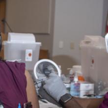 Nurse receives vaccine from her coworker, both are wearing masks