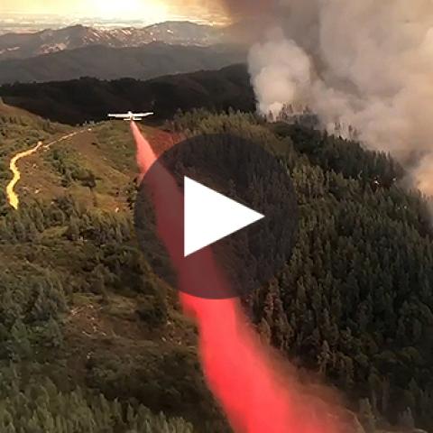 An airplane drops fire retardant on a wildfire