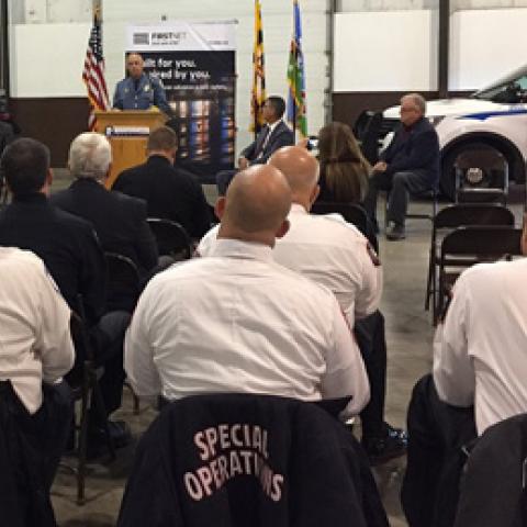 During an event marking one year of FirstNet in the State of Maryland, Sheriff Mullendore speaks at a podium in front of police vehicles