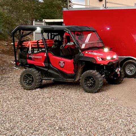 A truck, UTV, and transport trailer outfitted with FirstNet devices such as HPUE parked outside a Northwest Fire and Rescue station. 