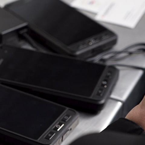 A Washington County law enforcement officer holds a FirstNet enabled device near several other devices being charged