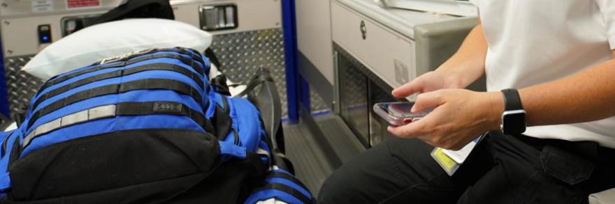 First responder in an ambulance holding a cell phone