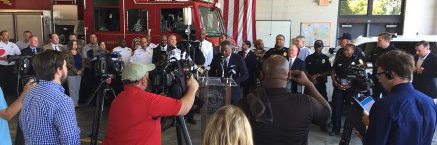 First responders inside a firehouse holding a press conference