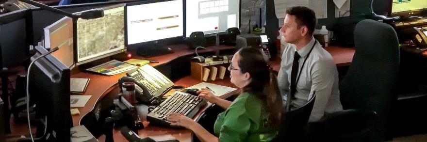 Two Miami-Dade dispatchers look at screens of information in their ECC