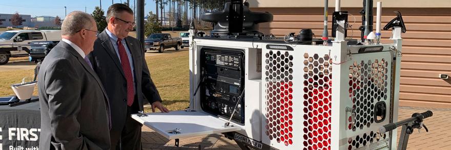 Two men stand beside a FirstNet Compact Rapid Deployable.
