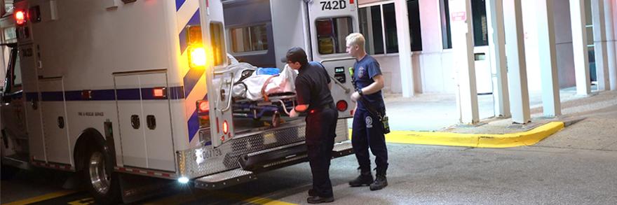 Two paramedics put a patient in the back of an ambulance.