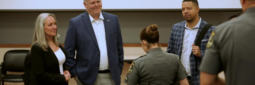 FirstNet Authority staff and Coverage Enhancement Workshop participants, including a uniformed law enforcement officer, stand in a circle speaking