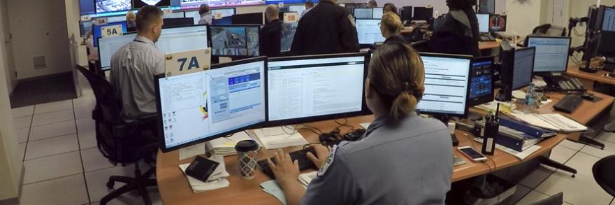 Emergency call ceneter with personel in front of three monitors  