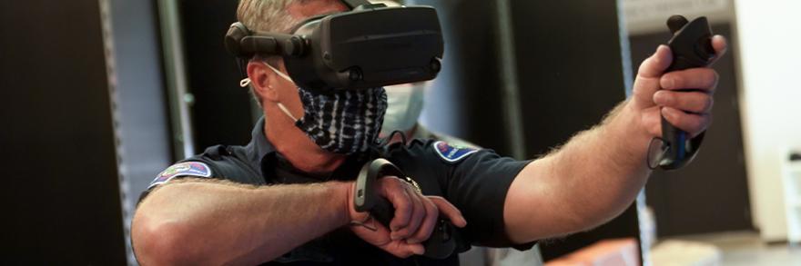 First responder wearing virtual reality glasses and holding controllers and gesticulates forward.