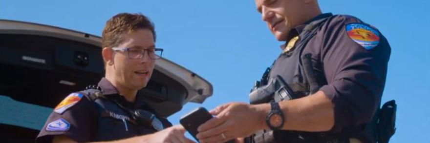 Two Town of Duck officers look at a smartphone 