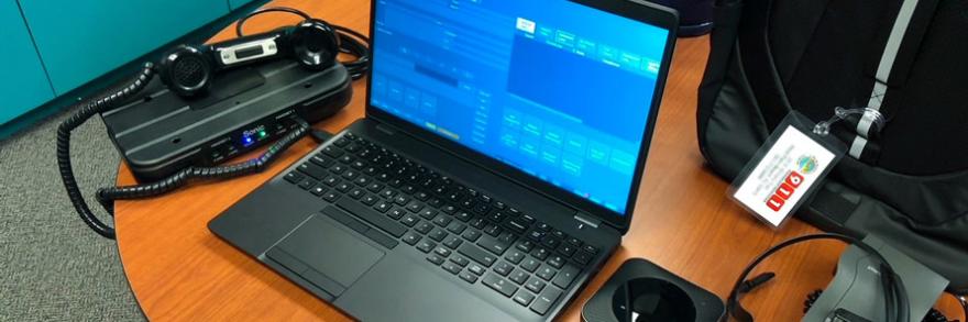 A phone, laptop, hot spot, and other dispatching equipment sit on a table.