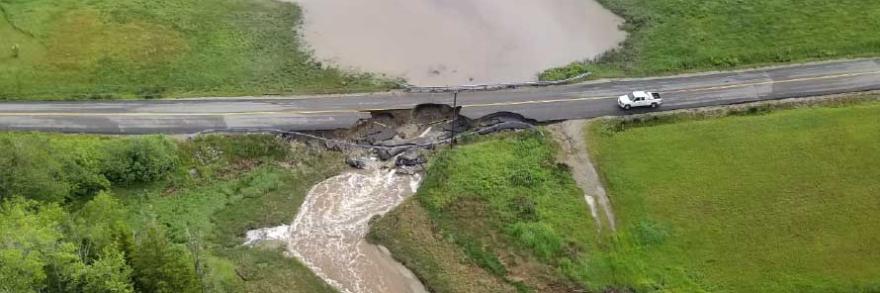 Aerial view of pickup truck near washed out road and flooded grass