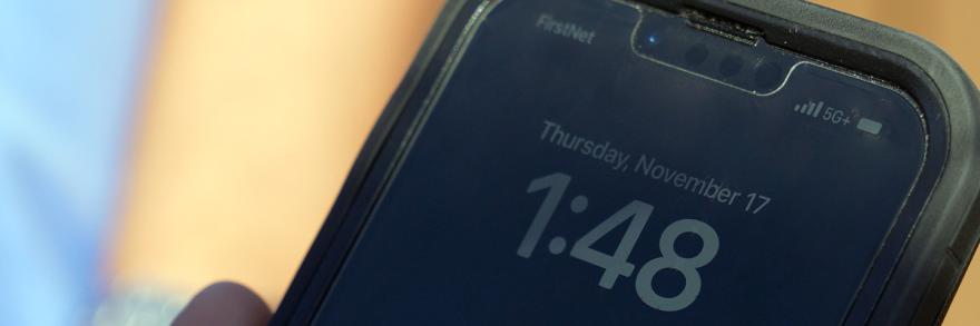 Close-up of smartphone. On screen: “FirstNet. 5G+. Tuesday, November 17. 1:48”