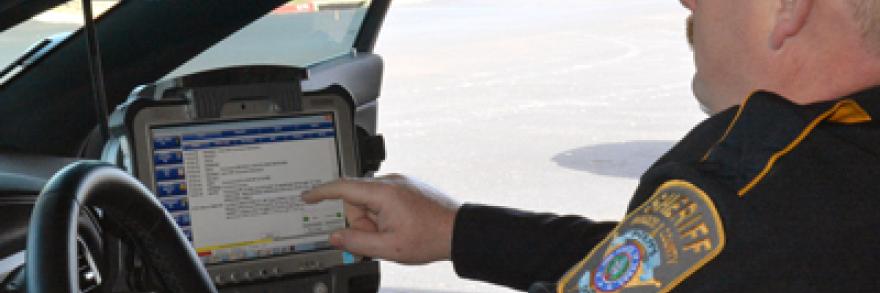A Brazos County Sheriff's Department officer looks at a screen inside of his patrol car