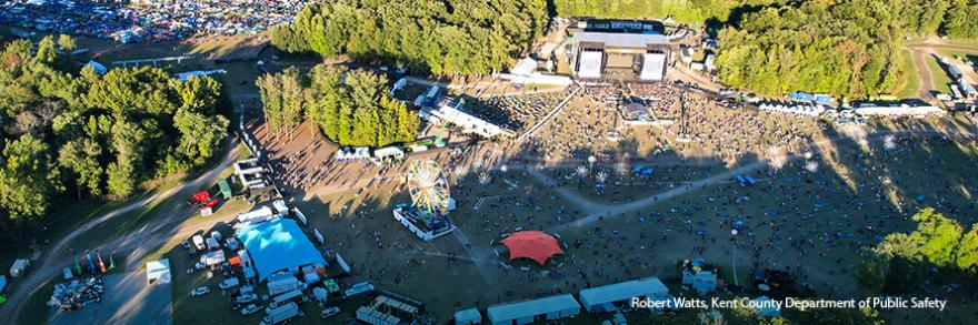An aerial view of the Firefly Musical Festival grounds, crowds of people at several live music stages around the grounds, a packed parking lot