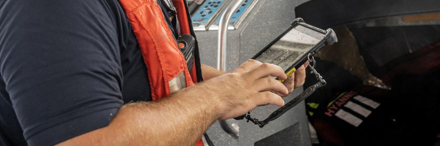 A Hyannis firefighter uses a tablet on a boat