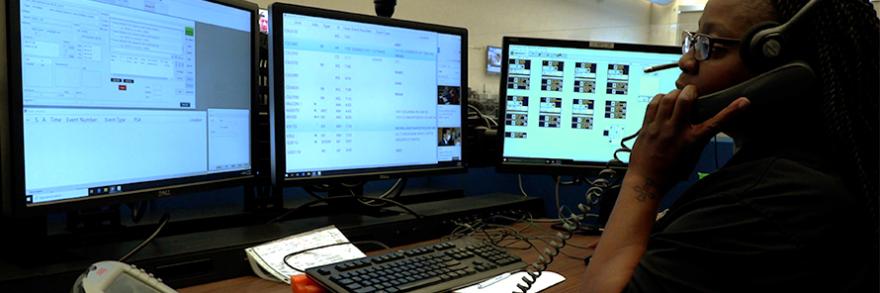 An emergency telecommunicator sits in front of computer monitor taking a call