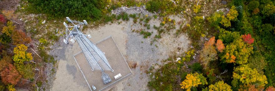 Overhead view of a Maine FirstNet cell tower in a rural area surrounded by trees.