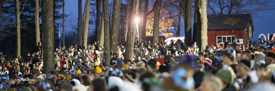 A group of people gathered in a wooded area attending the annual Groundhog Day ceremony