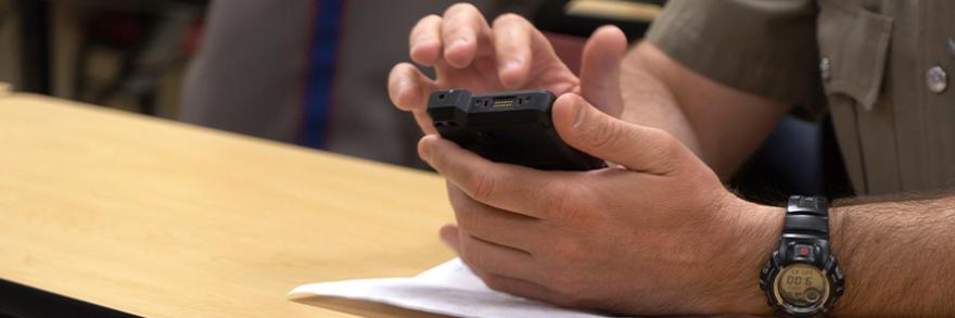 The hands of a first responder using a smartphone at a table. 