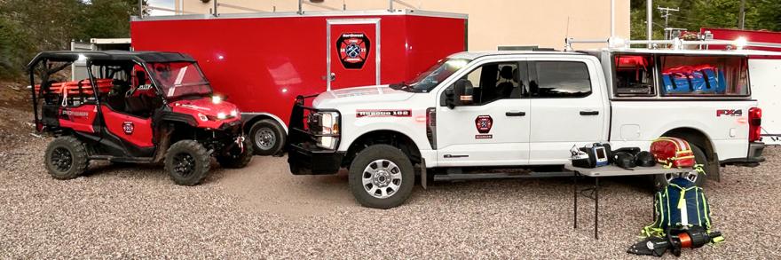 A truck, UTV, and transport trailer outfitted with FirstNet devices such as HPUE parked outside a Northwest Fire and Rescue station. 