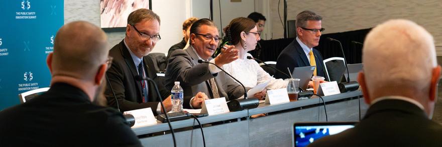 Board Chair Chief Richard Carrizzo, seated next to Executive Director Joe Wassel, gestures towards a fellow board member