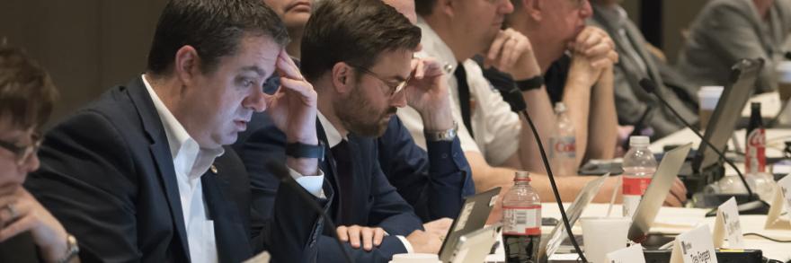 PSAC Spring Business Meeting highlights FirstNet network innovation, expansion; FirstNet Authority logo; PSAC members seated at a table in a meeting